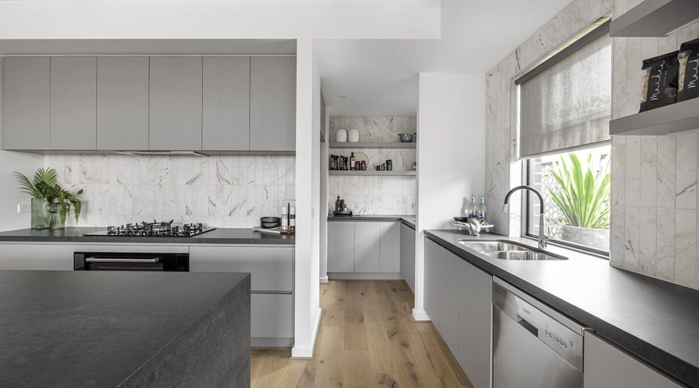 subway marble splashback balanced with a dark stone island bench with grey neutral palettes at the berrima 28
